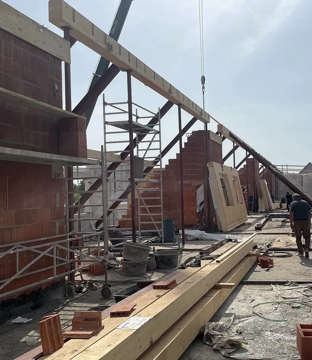 Dachaufstockung im Bau: Holzelemente und Ziegelwände auf der Dachebene eines Bestandsgebäudes